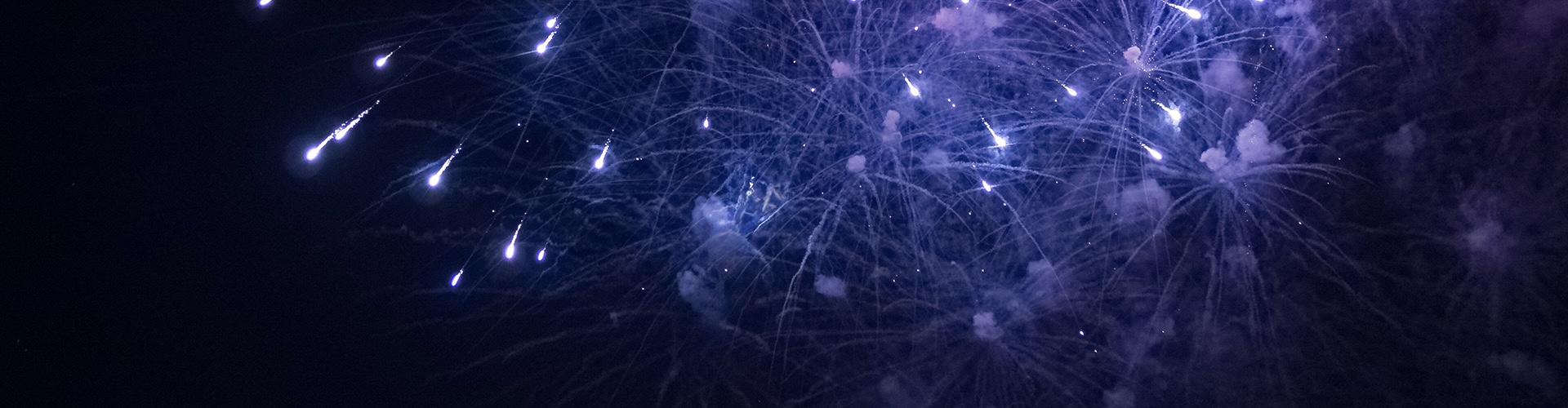Bright aerial fireworks bursting in the night sky with colorful sparks