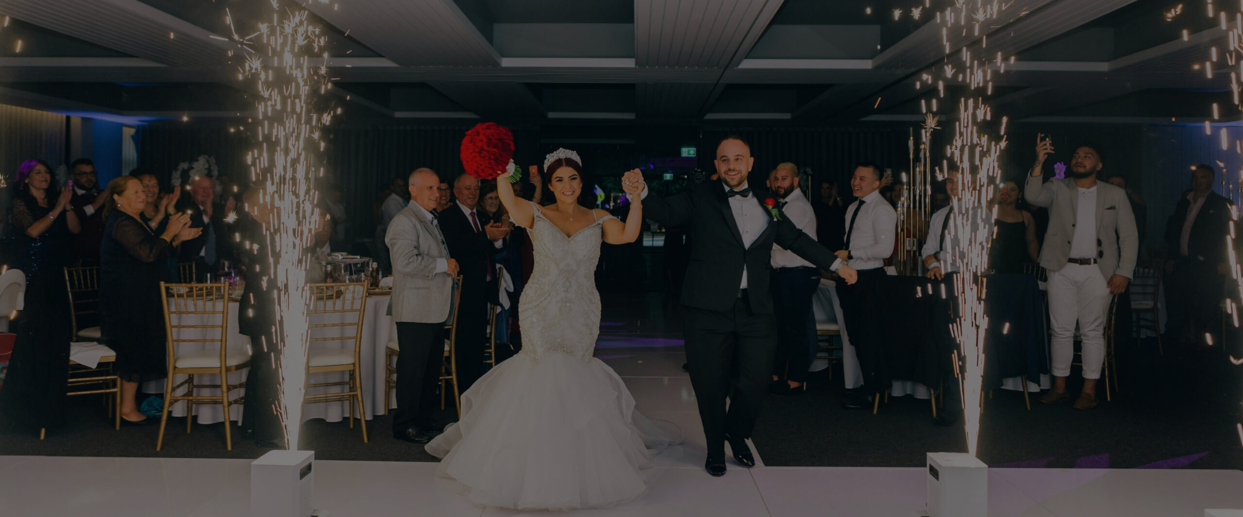 A wedding couple joyfully walk down the aisle, surrounded by glowing sparklers.